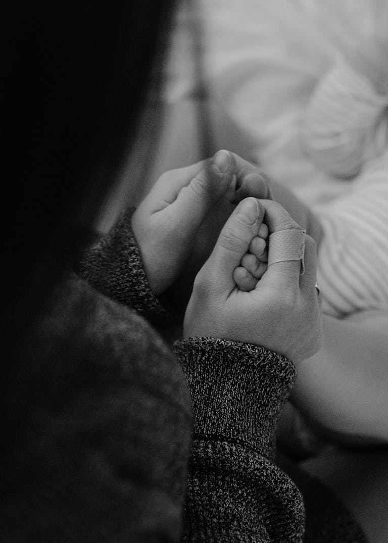 Winzige Hand eines Babys liegt in den Händen eines Erwachsenen – Schwarz-Weiß-Aufnahme